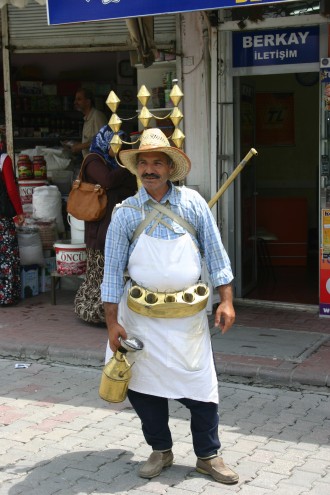 Türkischer Mann mit Messingkessel aus denen er ein heißes Süßholzgetränk verkauft