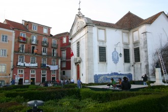 Lissabon in Portugal: Aussichtspunkt Santa Luzia vorbei. Kunsthandwerkerinnen fertigen Souvenirs, bunte Wäsche trocknet an opulent gekachelten Häuserfassaden
