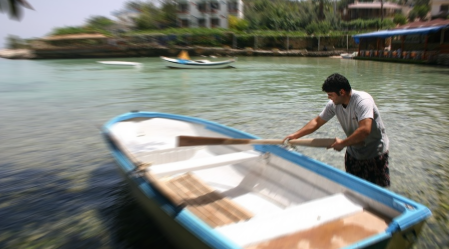 Ein Mann trägt ein Paddel am Boot