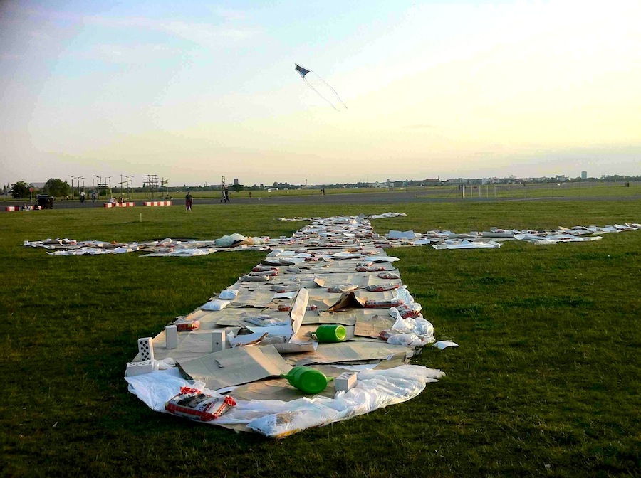 Säcke mit Spielsand beschweren ein Pappe-Flugzeug mit Giekannen