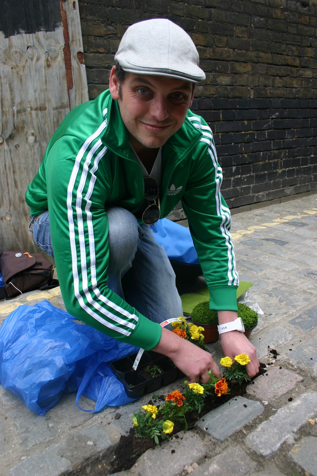 Steve Wheen im Osten Londons, nimmt einen Haufen Blumenerde und füllt damit einen breiten Spalt im Kopfsteinpflaster einer Seitengasse der Voss Street auf.